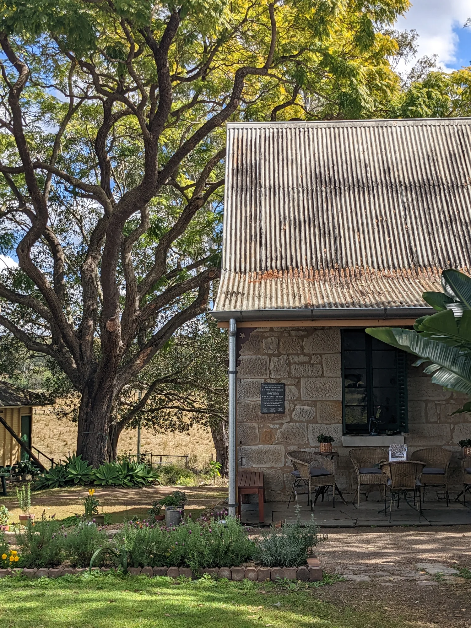 Stone heritage building and mature tree within a garden setting