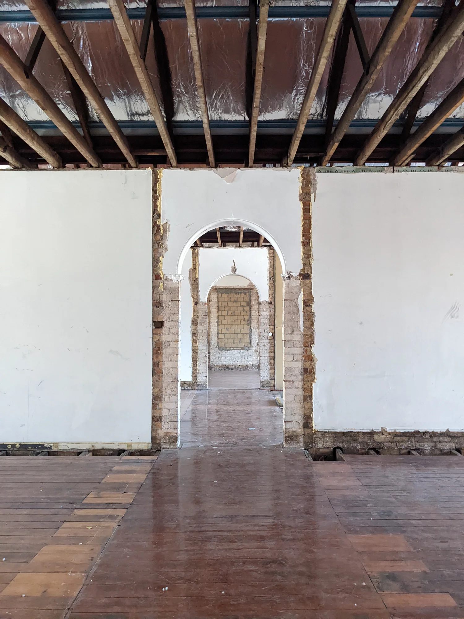 Historic interior with exposed roof structure and a sequence of arched openings